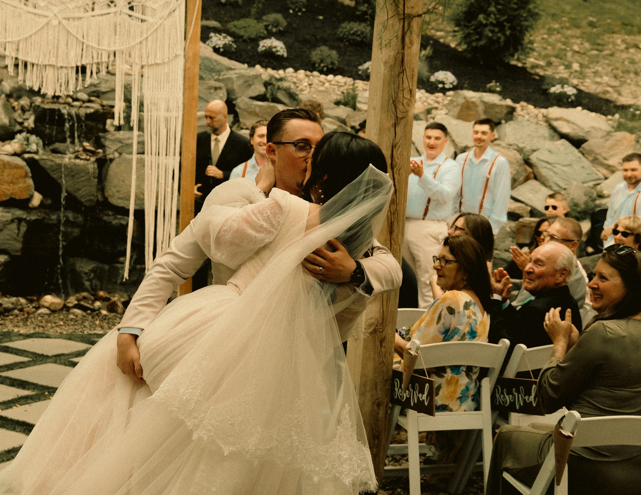 The first kiss at an outdoor ceremony while the guests applaud