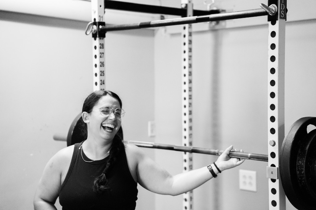 A lifter laughing mid-set at the squat rack, black and white